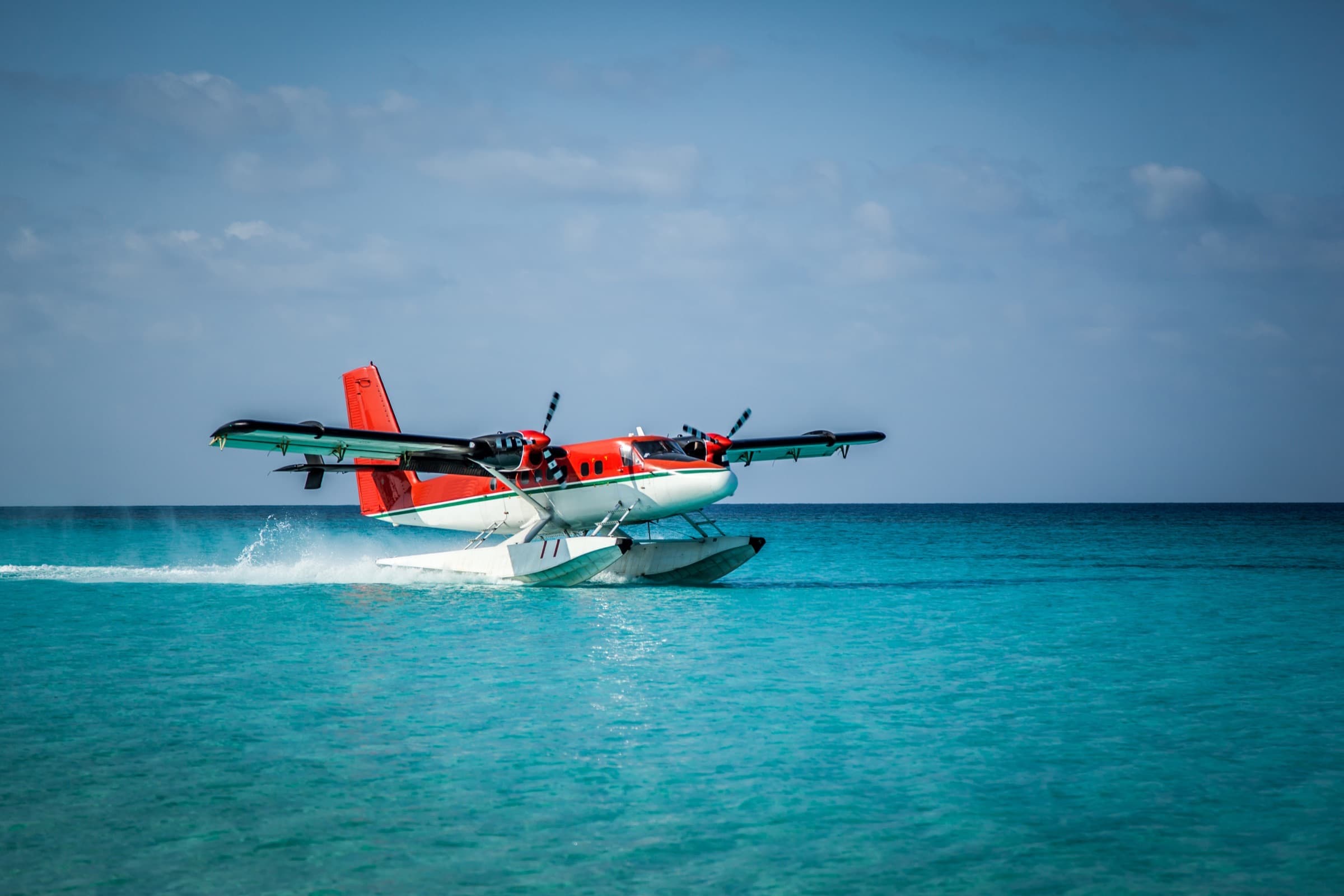 A seaplane touching down on clear turquoise water