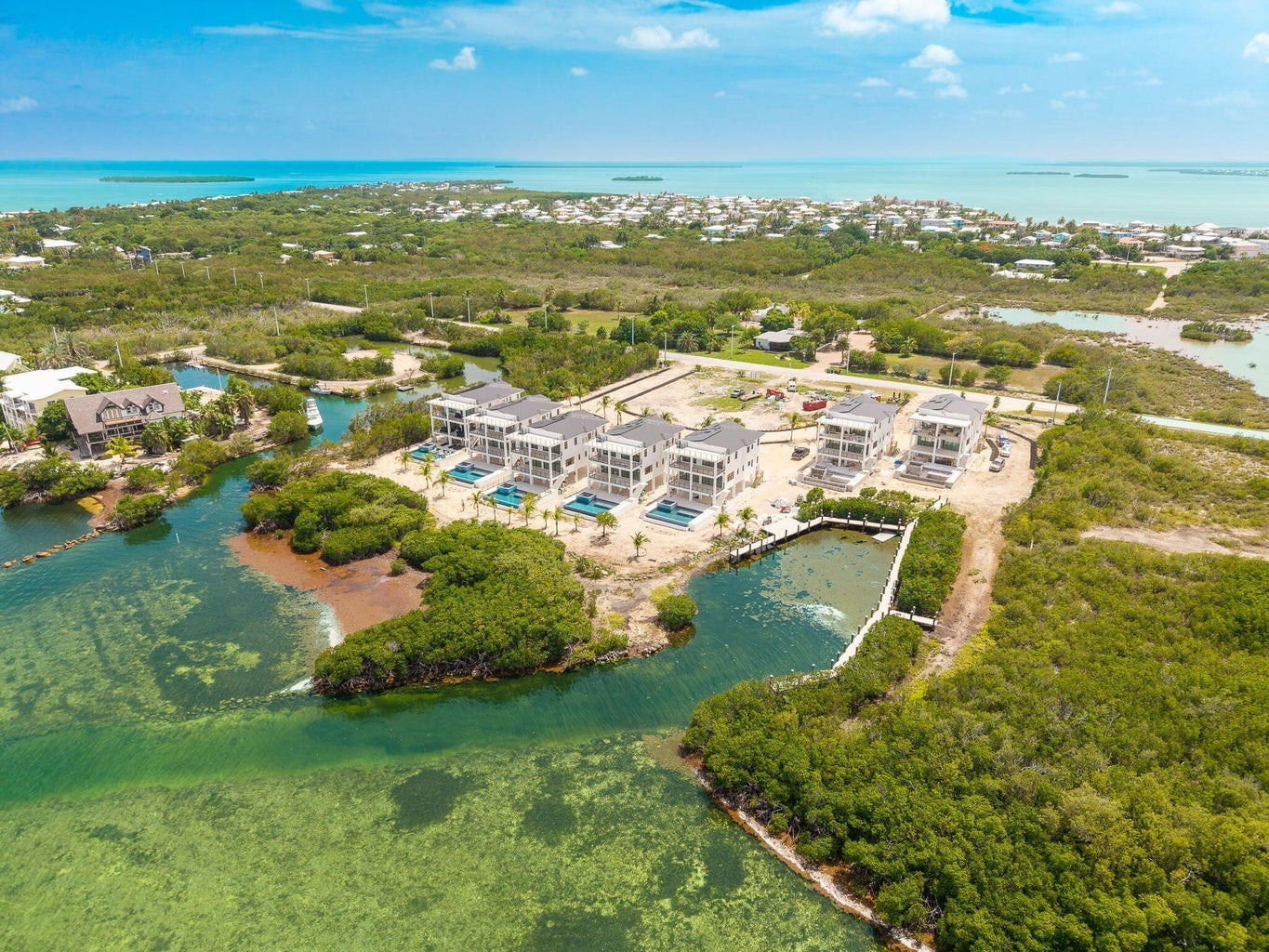 High aerial view of the Seven Palms Cove residences beside a mangrove-lined waterway, with open water and Summerland Key beyond