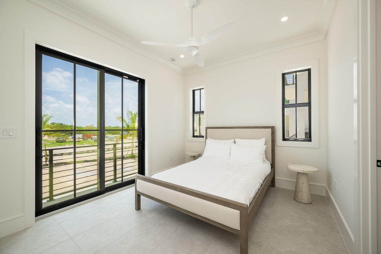 Bedroom with a queen bed and tall sliding glass doors to a railed balcony