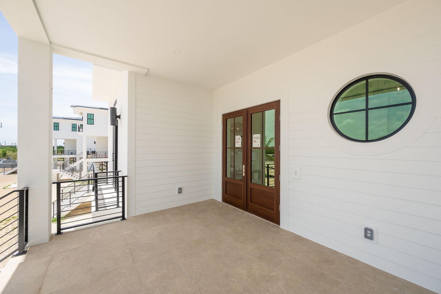 Covered front porch with wood double doors, an oval porthole window and white shiplap walls