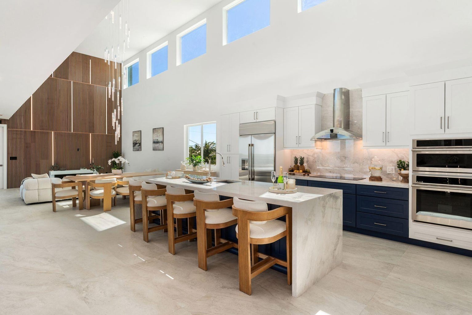 Open kitchen and dining area with stone counters, navy lower cabinets and stainless appliances