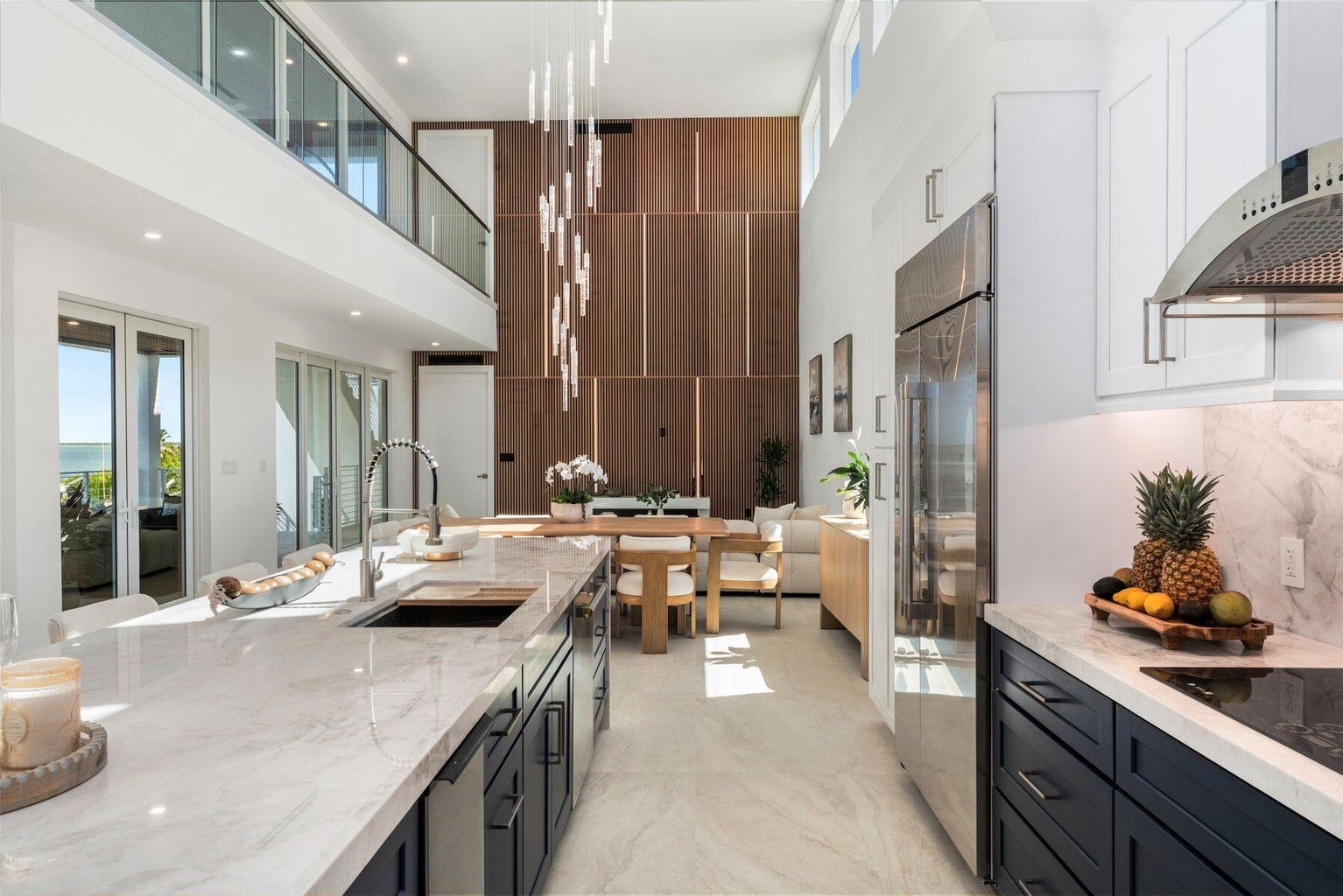 Kitchen island looking toward the dining table, great room and a glass-railed upper landing