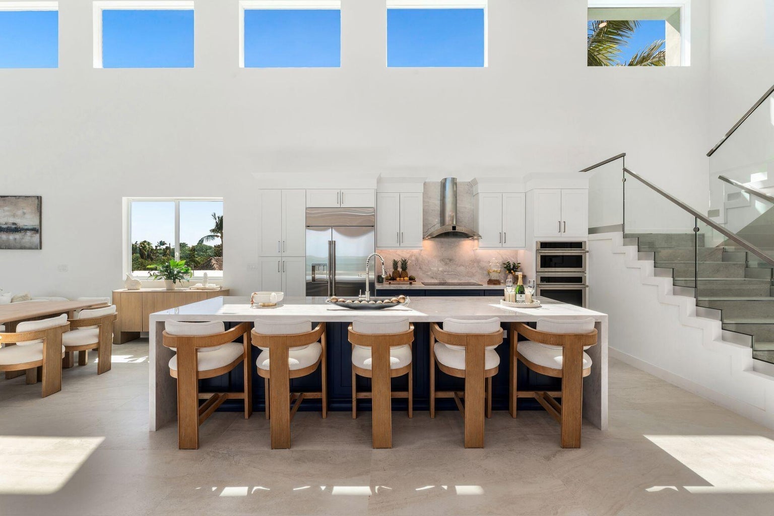 Kitchen with a long waterfall island, five counter stools and clerestory windows above