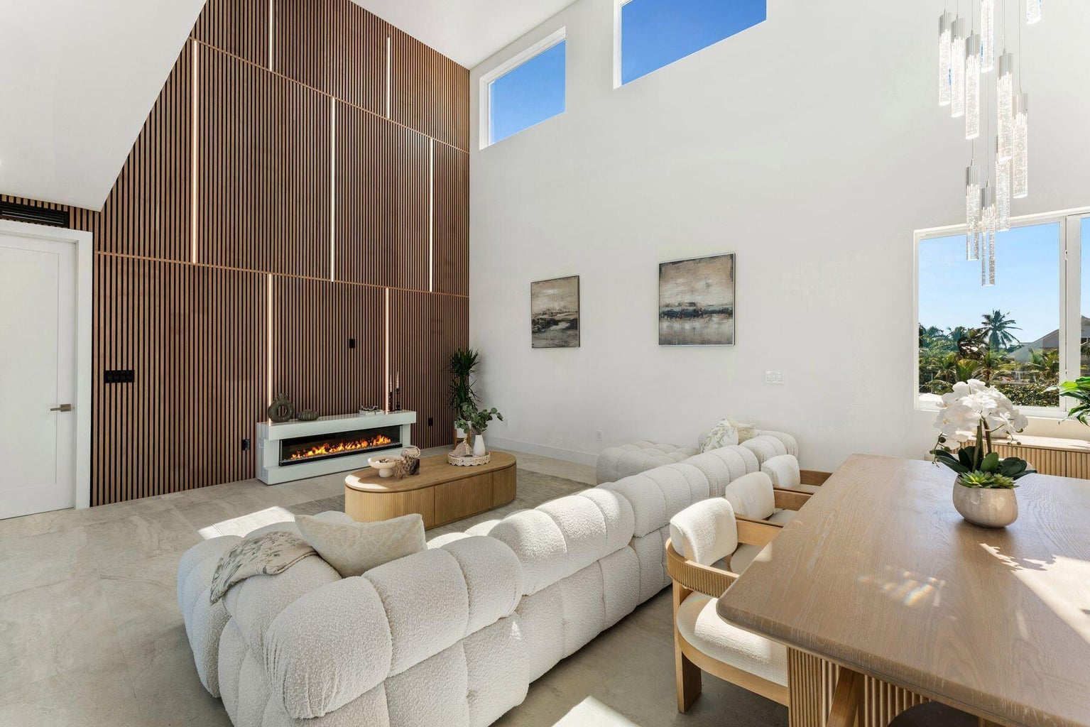 Double-height living room with a slatted wood feature wall, linear fireplace and white sectional