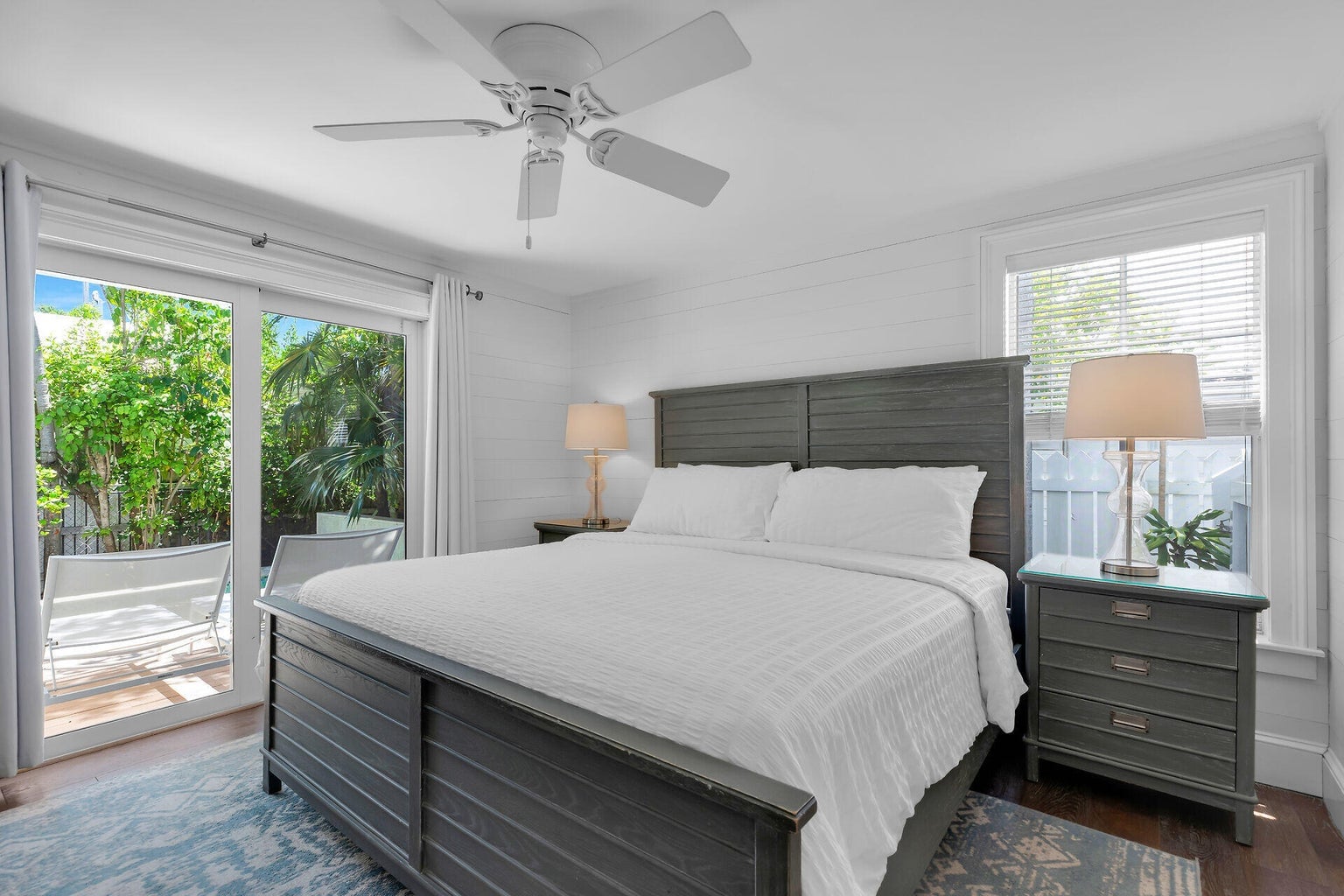 Bedroom with a gray king bed and sliding glass doors opening to the pool deck