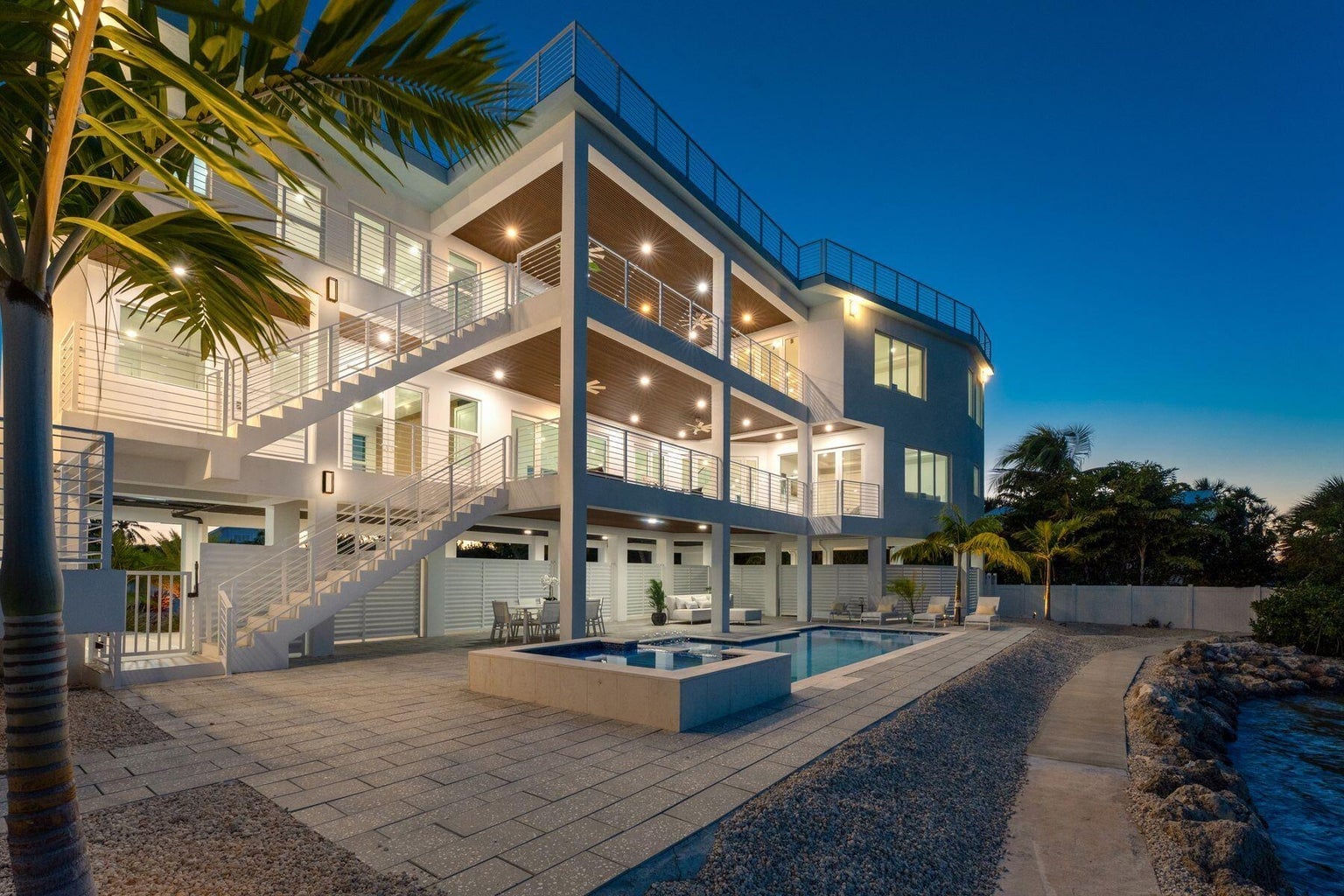Pool, raised spa and three levels of lit covered terraces at twilight