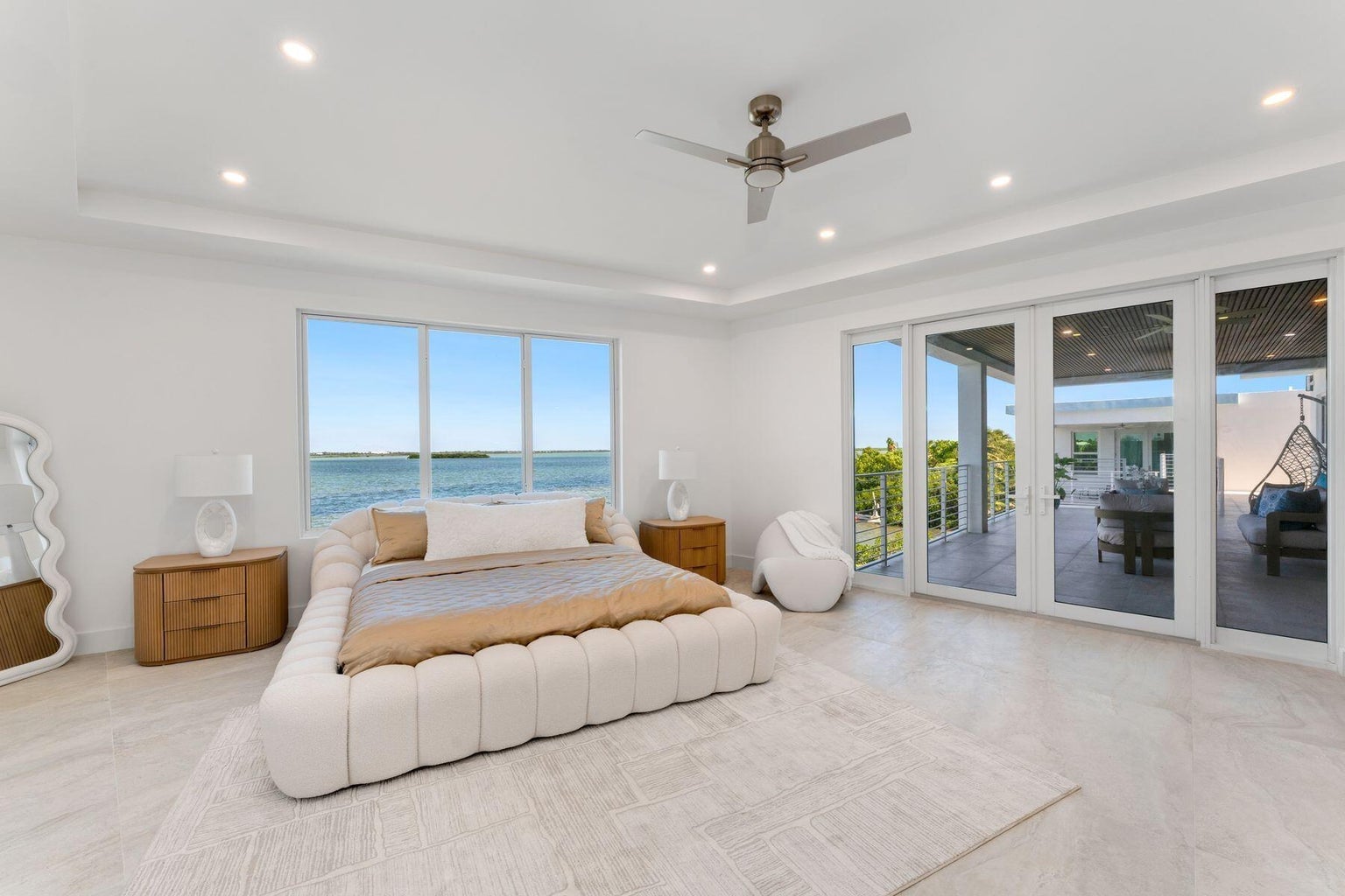 Bedroom with a tray ceiling, water-view windows and sliding glass doors to a covered terrace