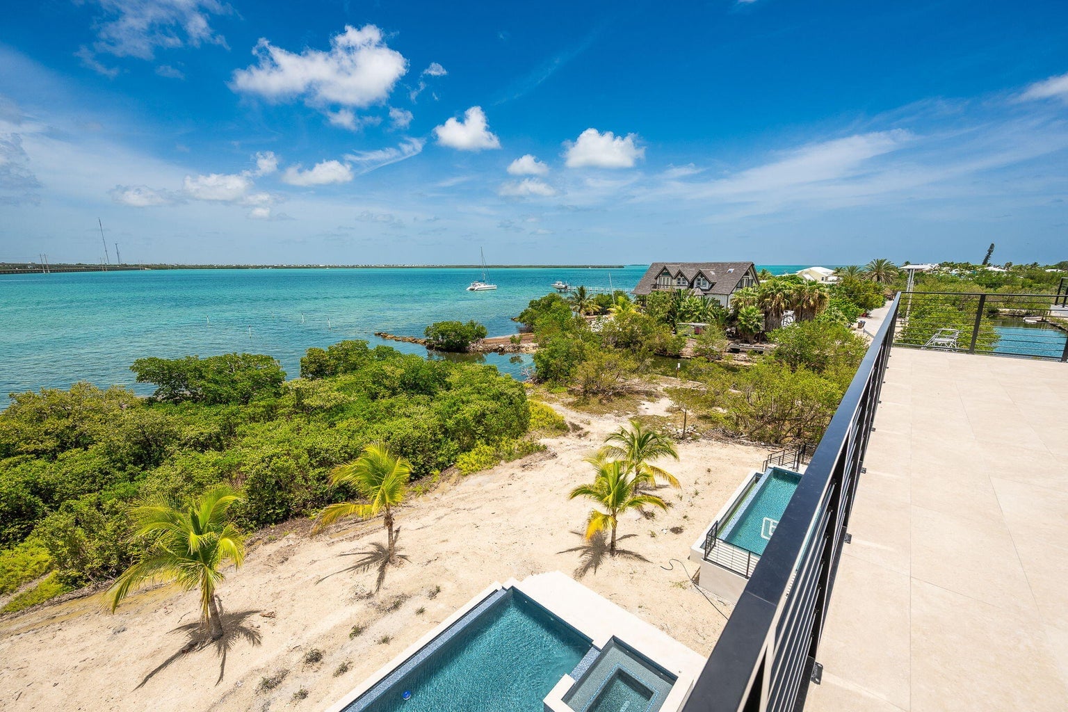 View from the roof's edge over pools, palms and mangroves to open water