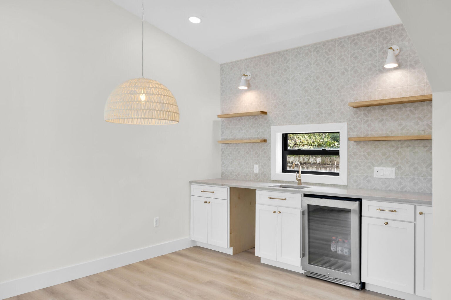 Wet bar with a beverage fridge, open wood shelves, wall sconces and patterned tile
