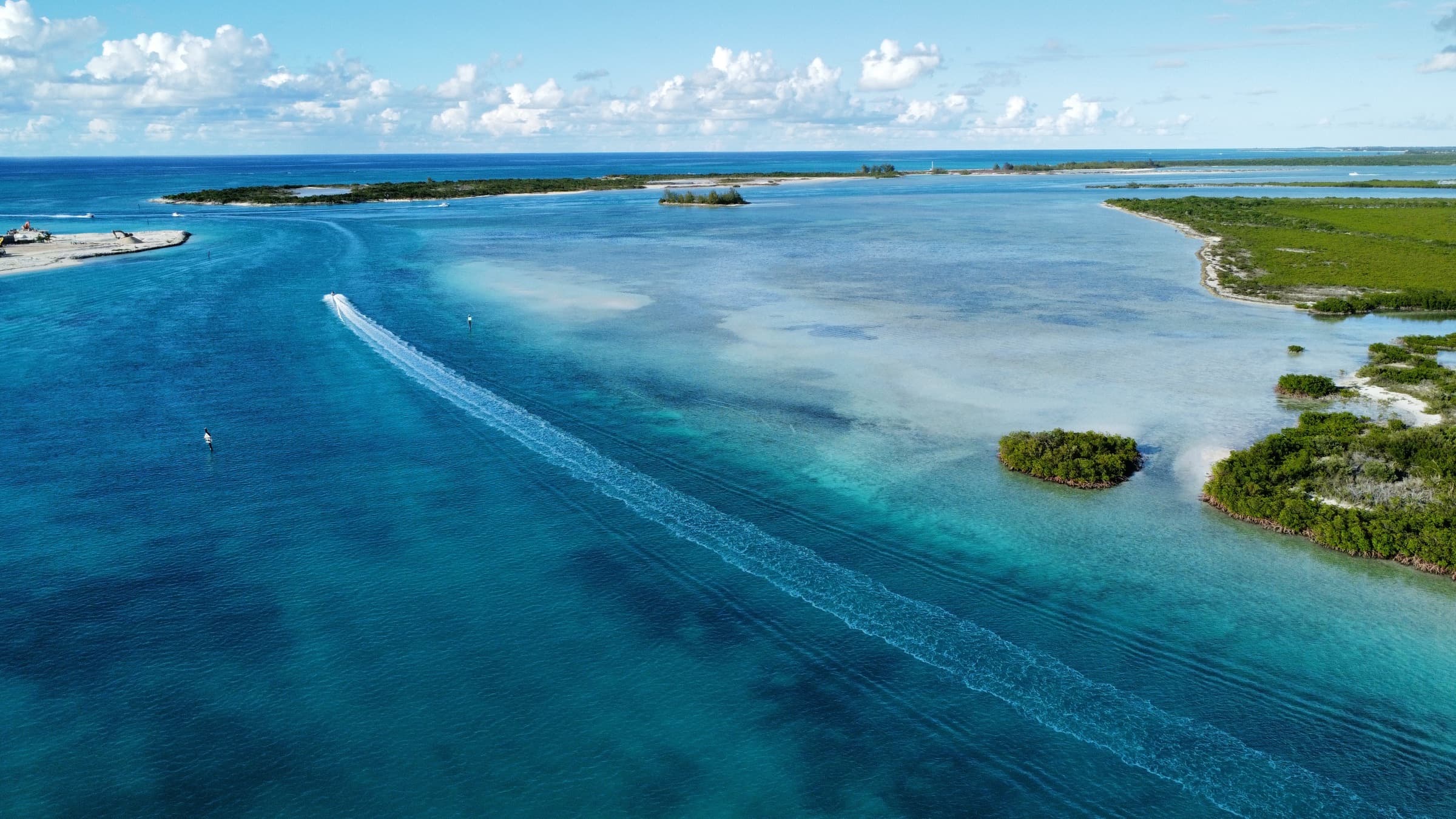 Aerial view of a boat crossing turquoise backcountry water among mangrove islands