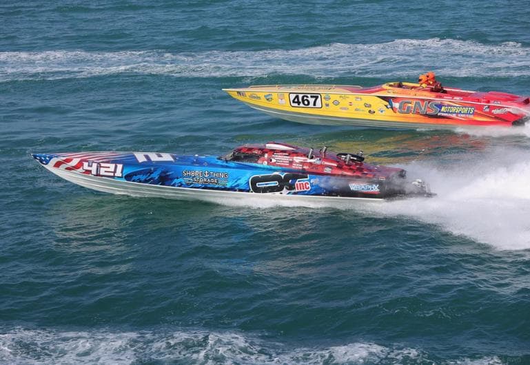 Two offshore powerboats, numbers 421 and 467, racing side by side across open water, throwing spray behind them.